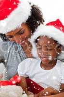 Composite image of mother and daughter opening a christmas gift