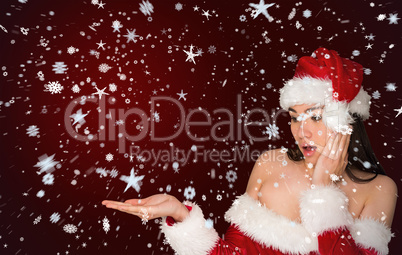 Surprised brunette in santa outfit presenting with hand