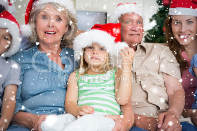 Composite image of happy multigeneration family wearing santa ha