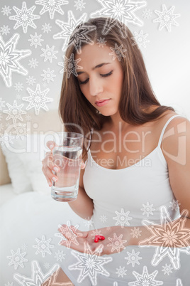 Woman looking down at the two pills she is going to take with wa