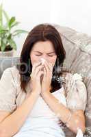 Portrait of a sick woman blowing her nose while sitting on the s