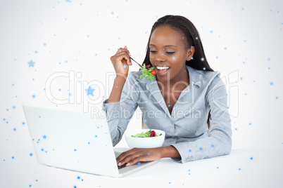 Businesswoman working with a laptop while eating a salad