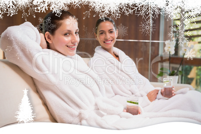 Smiling women in bathrobes sitting on couch