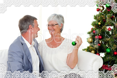 Mature couple sitting on sofa with a christmas tree