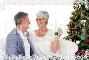 Mature couple sitting on sofa with a christmas tree