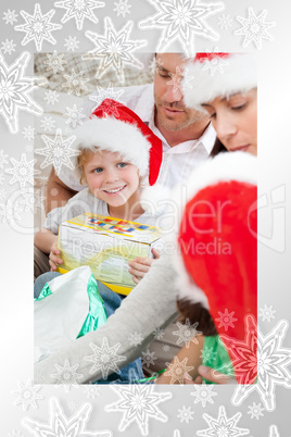 Happy boy holding a christmas gift sitting on the floor