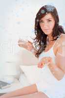Attractive brunette female taking some pills while sitting