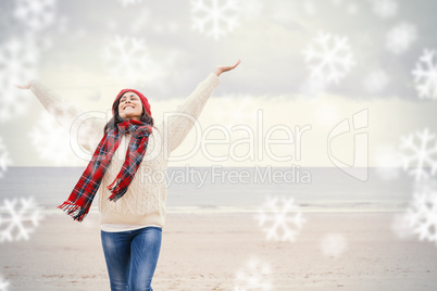 Woman in warm clothing stretching arms on beach