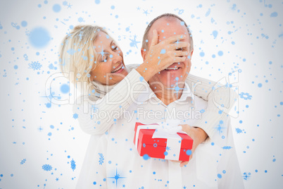 Older woman covering her partners eye while holding present