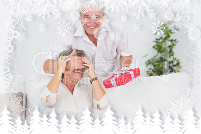 Composite image of old man hiding eyes of his wife for a gift