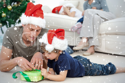 Father and son unwrapping a present lying on the floor