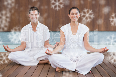 Attractive couple in white sitting in lotus pose smiling at camera