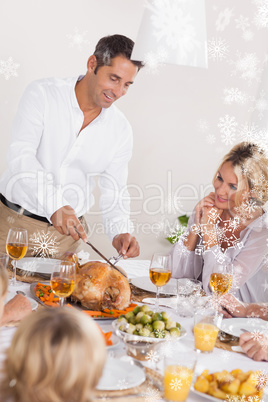 Composite image of father carving the turkey at the head of the