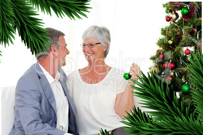 Mature couple sitting on sofa with a christmas tree