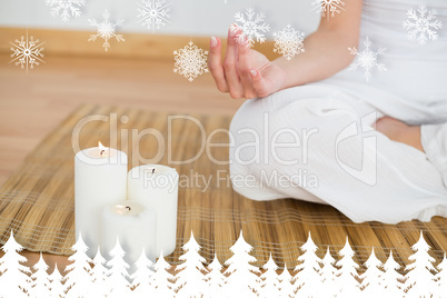 Woman sitting in lotus pose beside white candles