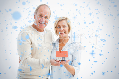 Happy mature couple with model house