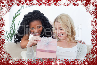 Composite image of two women look inside a pink box
