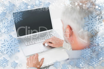 Closeup rear view of a grey haired man using laptop at desk