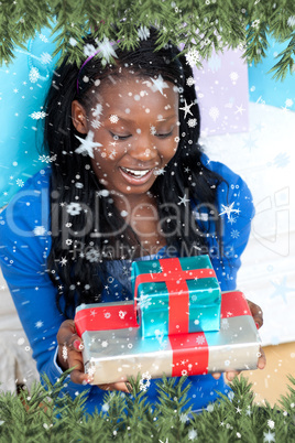 Composite image of smiling woman holding a present sitting on th