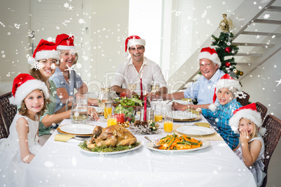 Composite image of happy family in santa hats having christmas m