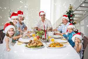 Composite image of happy family in santa hats having christmas m