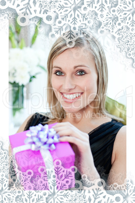 Glowing woman opening a gift sitting on a sofa