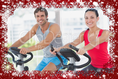 Smiling young couple working out at spinning class