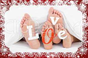 Composite image of pair of feet under duvet with love text