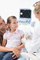 Composite image of girl receiving injection by pediatrician