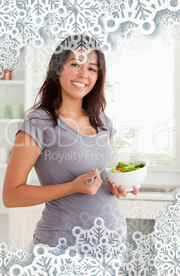 Gorgeous pregnant woman holding a bowl of salad while standing