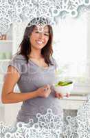 Gorgeous pregnant woman holding a bowl of salad while standing