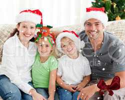 Portrait of a happy family with christmas hats sitting on the so