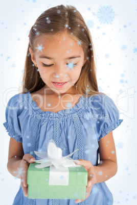 Composite image of cute little girl holding a wrapped gift