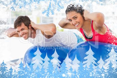 Fit couple exercising on fitness balls in gym