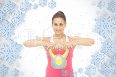 Smiling sporty brunette holding grey and yellow kettlebell