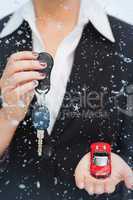Composite image of woman holding key and small car in her palm