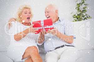 Composite image of surprising old woman receiving a gift