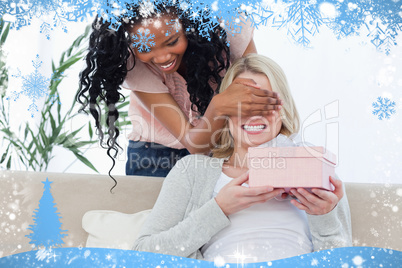 Woman holding a present has her eyes blocked by her friend