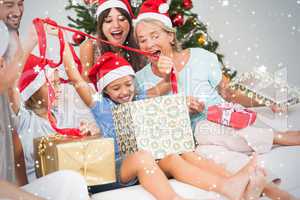 Composite image of happy family at christmas opening gifts toget