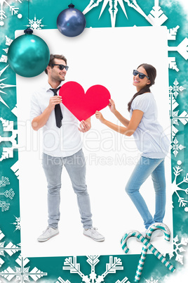 Composite image of hipster couple smiling at camera holding a heart