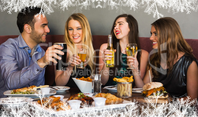 Composite image of friends having dinner together and toasting