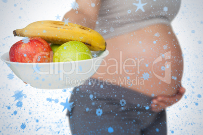 Pregnant woman showing fruit bowl to camera