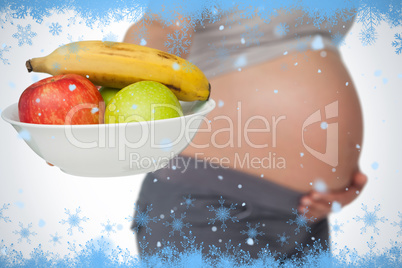 Pregnant woman showing fruit bowl to camera