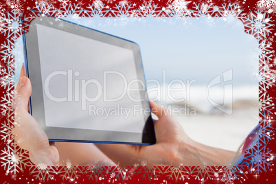 Woman sitting on beach in deck chair using tablet pc