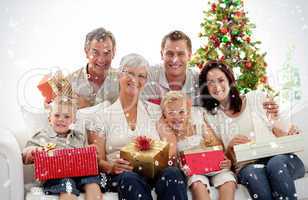 Composite image of family holding christmas presents at home