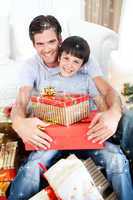 Composite image of happy father and son holding christmas gifts