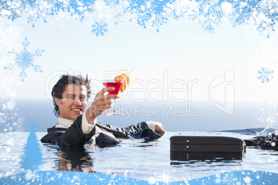 Cheerful businessman relaxing in a swimming pool with a cocktail