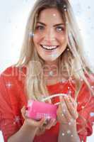 Composite image of cheerful woman discovering necklace in a gift box