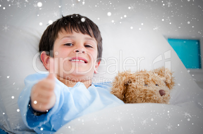 Composite image of little boy hugging a teddy bear lying in a ho