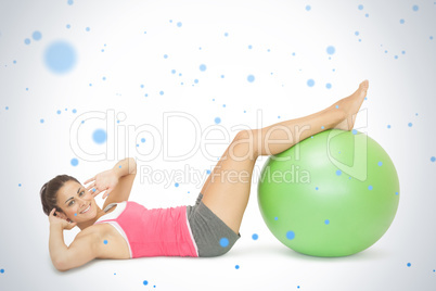 Smiling sporty brunette doing sit ups with exercise ball